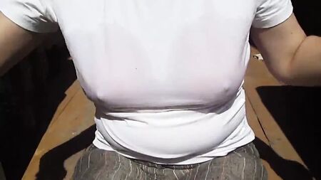 Une fille enlève son soutien-gorge de bain mouillé sous son t-shirt trempé