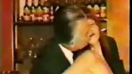 Des hommes d'âge mûr en costume se font taquiner par une serveuse de bar mature en tweed