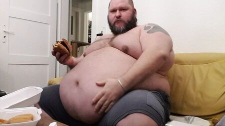 Superchubby SOC - un gros bonhomme en train de manger un énorme hamburger et des rondelles d'oignon