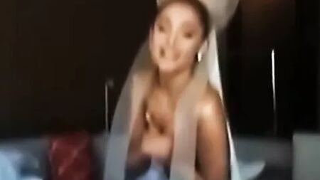 Ariana Grande, seins nus, se tenant les seins en coulisses