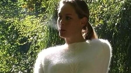 Une femme vêtue d'un pull duveteux fume