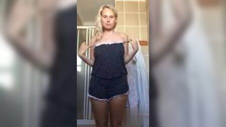 Une blonde aux gros seins se déshabille dans sa salle de bain