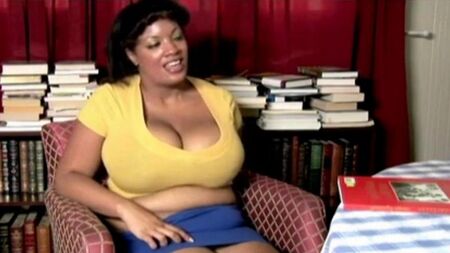 La grosse femme Nigersh s'assoit sur une chaise et enlevant sa culotte caresse une chatte