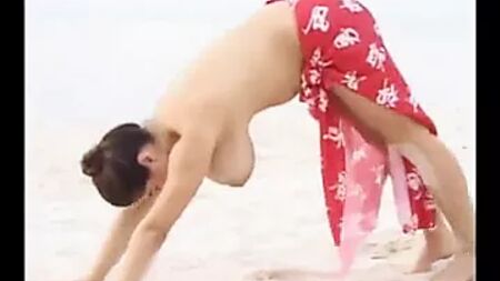 Une femme aux seins énormes s'étire sur la plage